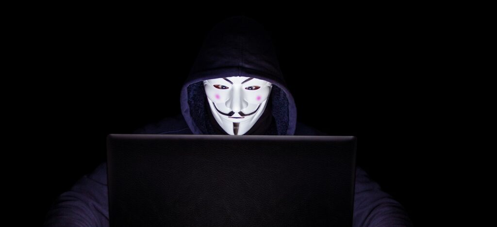 Anonymous-masked hacker at laptop