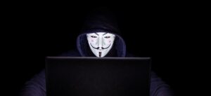 Anonymous-masked hacker at laptop