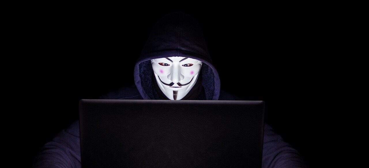 Anonymous-masked hacker at laptop